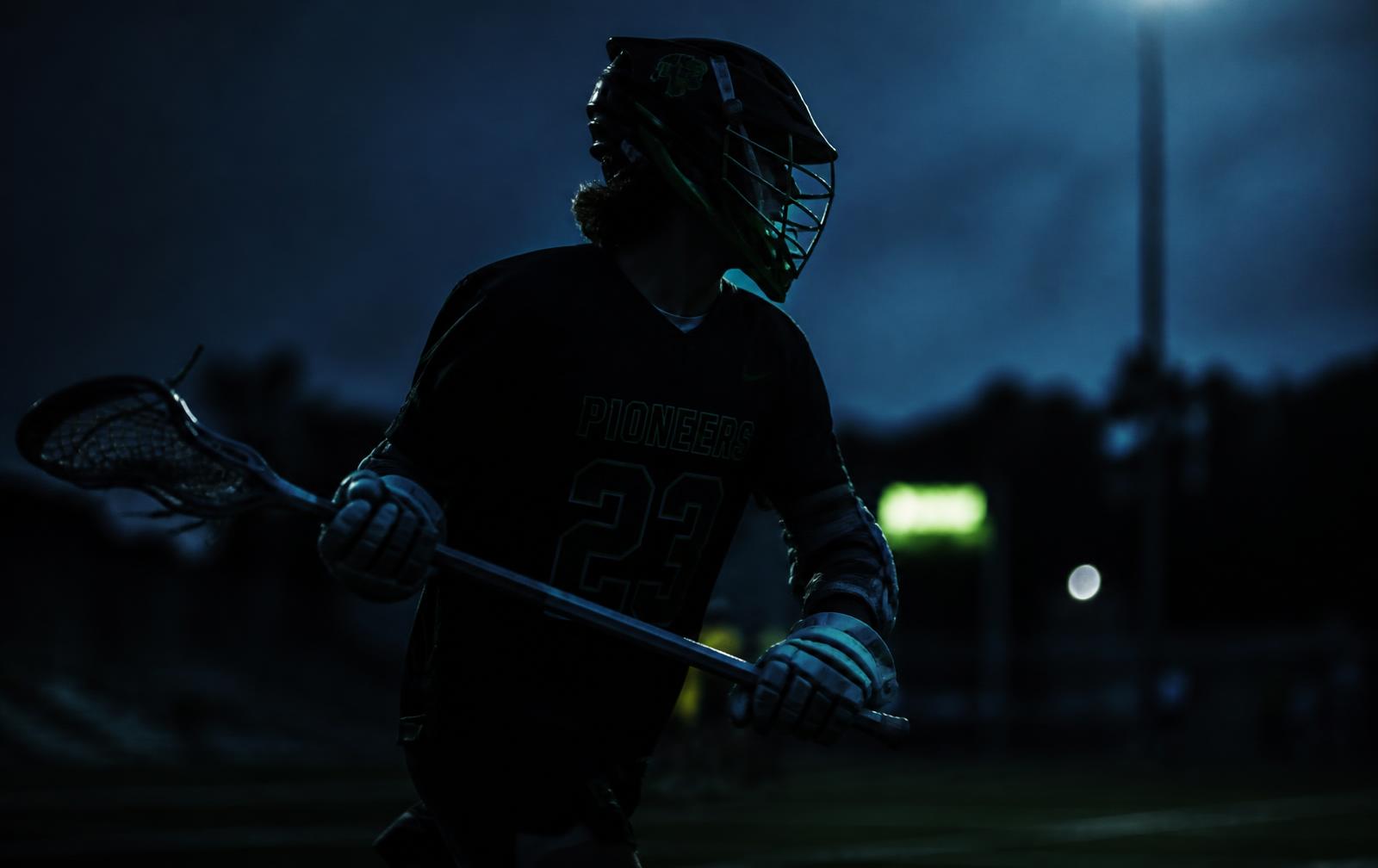 Lacrosse player under stadium lights at dusk